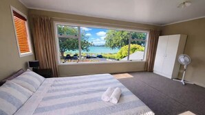 Quarto com cama grande, vista para um lago, guarda-roupa e ventoinha.