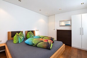 Un dormitorio moderno con cama, cabecero de madera y un armario.