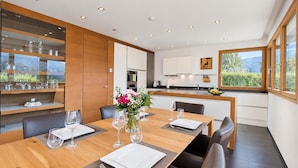 Un espace repas moderne avec une table en bois dressée pour quatre personnes, entourée de fauteuils en cuir foncé.