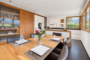 Un espace repas moderne avec une table en bois dressée pour quatre personnes, entourée de fauteuils en cuir foncé.
