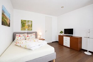 Une chambre à coucher moderne, équipée d’un lit, d’une télévision, d’un bureau et d’une lampe sur pied.