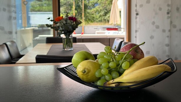 A dining table with a fruit bowl containing apples, grapes, and bananas. - Villa in Tyrol with pool (Stanz bei Landeck)