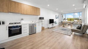 A modern kitchen with white cabinets, a built-in oven, and a dining area with a table and chairs. - Stylish 2BR + Sofa Bed Apartment | Prospect (Prospect)