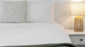 A neatly made bed with two pillows, a bedside lamp, and a wall-mounted abstract painting. - Stylish 2BR + Sofa Bed Apartment | Prospect (Prospect)