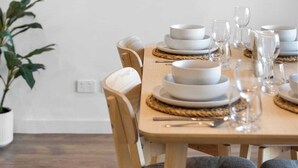 A dining area with a table set for four, a potted plant, and a large abstract painting on the wall. - Stylish 2BR + Sofa Bed Apartment | Prospect (Prospect)