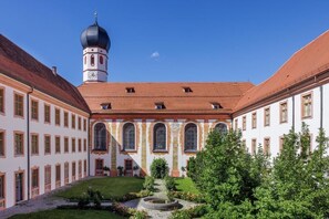 A courtyard with a central building featuring arched windows and a tower with a dome. - Kloster Beuerberg  (Eurasburg)
