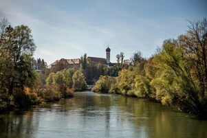 A river with trees and a building with a tower in the background.