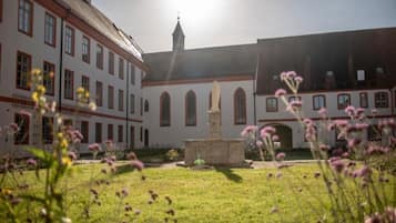 A courtyard with a fountain, surrounded by buildings with arched windows and a tower.