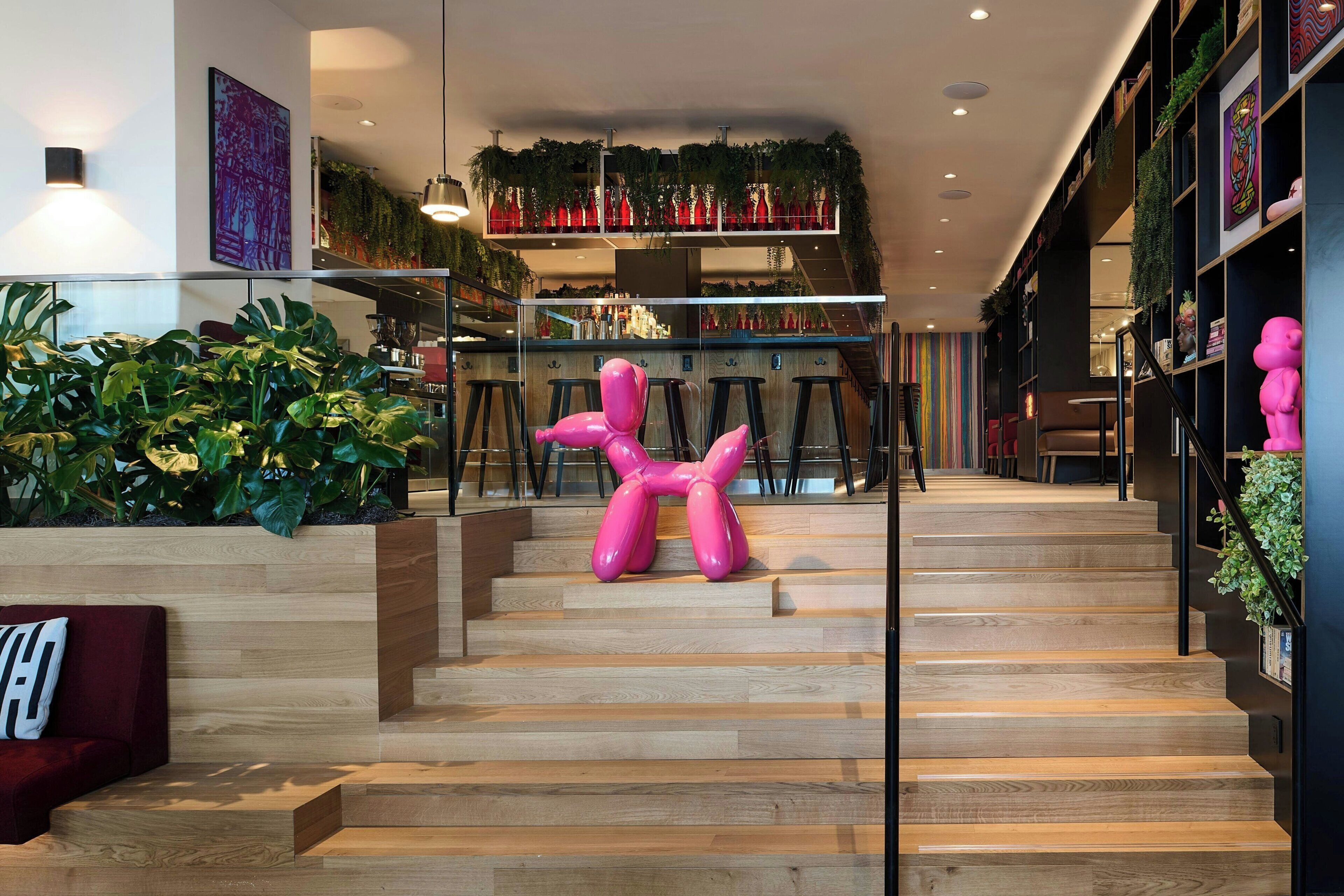 Una escalera de madera con una escultura rosa en el centro.
