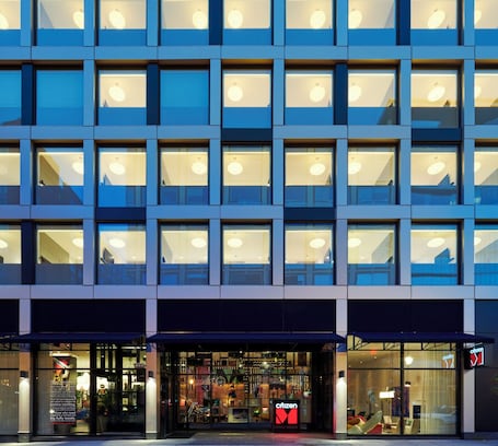 A modern building with multiple floors, large windows, and a storefront with a visible sign.