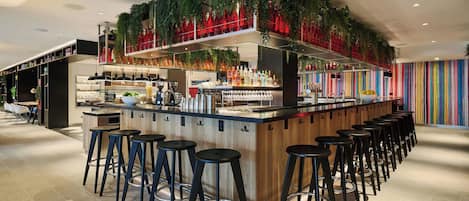 A bar area with stools, a counter, and shelves with bottles.