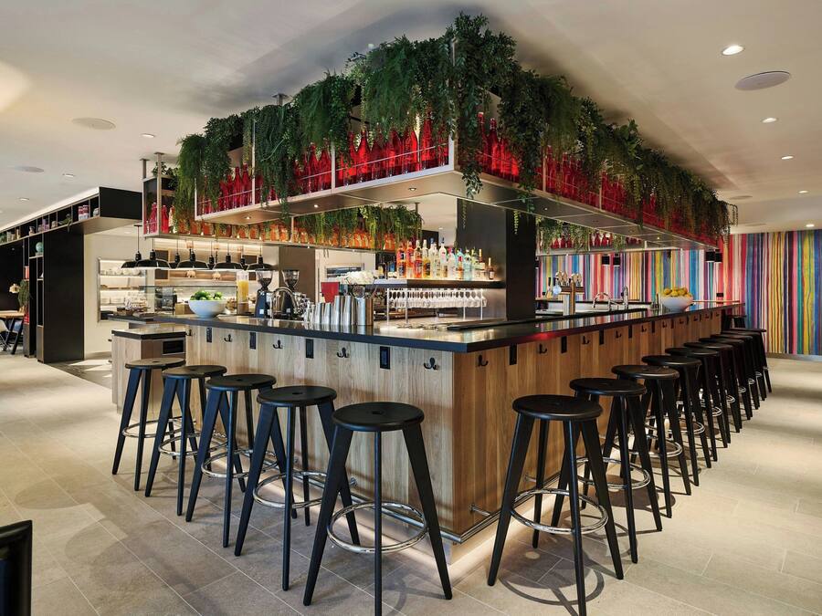 A bar area with stools, a counter, and shelves with bottles.