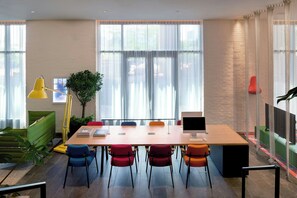 A modern office space with a long table, multiple chairs, a desk with a computer, and a plant. - citizenM Washington DC Georgetown (Washington)