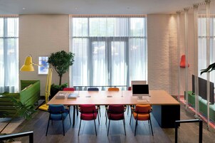 Un espace de bureau moderne comprenant une grande table, plusieurs chaises, un bureau avec un ordinateur et une plante.