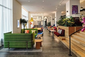 Een modern interieur met zithoeken, een trap en uitzicht op de omgeving.