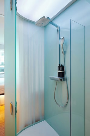 Een moderne badkamer met een douchecabine van glas, een handdouche en een wandmengkraan.