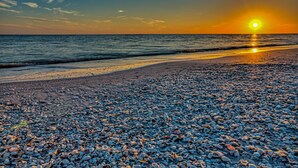 A beach with pebbles and the ocean. - Beachfront 2BR Condo at Casa Ybel Resort: Top Floor, Private Balcony Ocean Views (Sanibel)