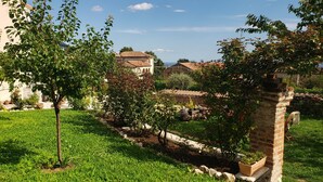 Un jardin avec des arbres, un mur de pierre et un bâtiment doté d’un toit en tuiles.