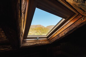 Ein Dachfenster mit Blick auf eine gebirgige Landschaft.