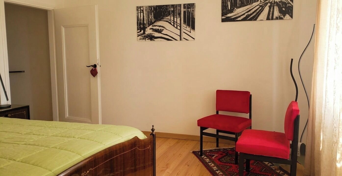 Une chambre à coucher comprenant un lit, une chaise, une porte et deux tableaux accrochés au mur.
