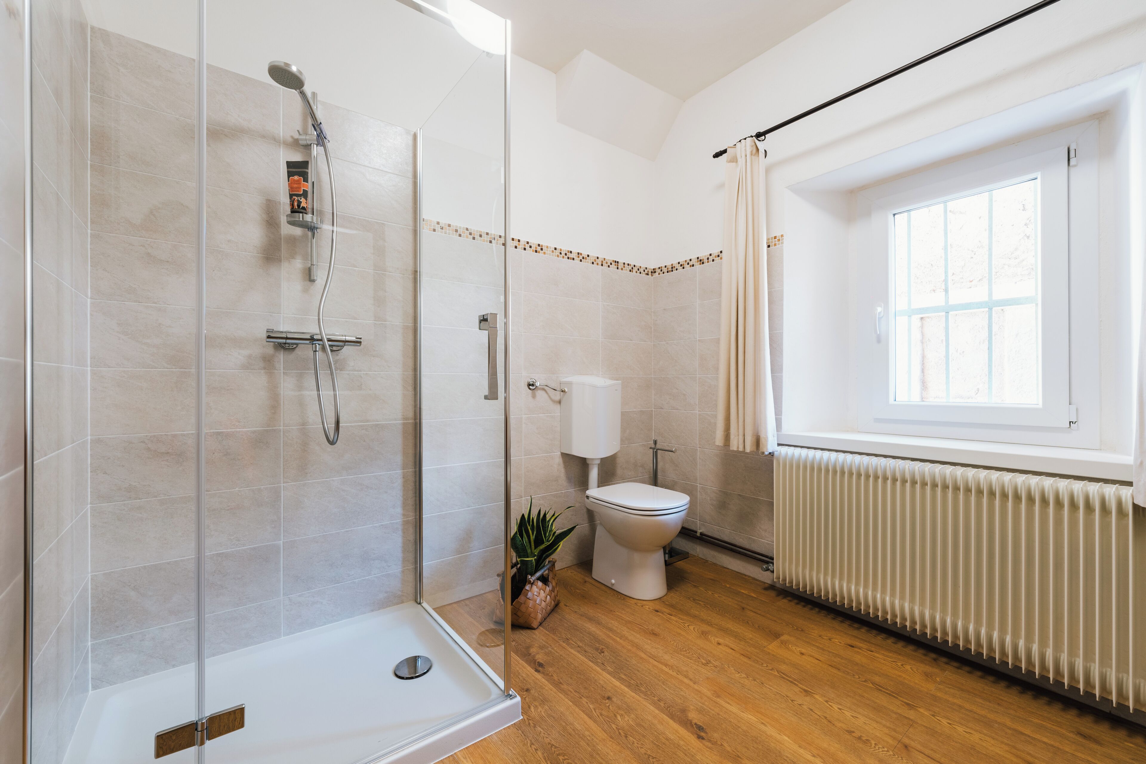Ein modernes Badezimmer mit Duschkabine, Toilette und Handtuchheizkörper.