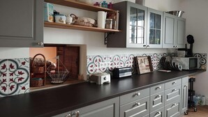 Een keuken met een donker aanrecht, grijze kastjes, een magnetron en een broodrooster.