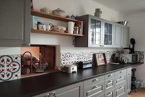 Une cuisine avec un plan de travail foncé, des placards gris, un four à micro-ondes et un grille-pain.