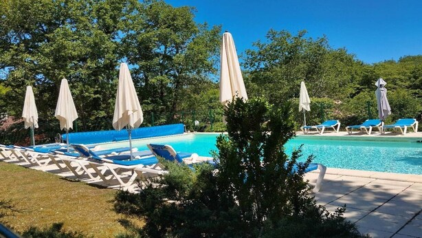 A swimming pool with lounge chairs and umbrellas, surrounded by trees. - Cottage in Lachapelle-Auzac with Pool (LACHAPELLE AUZAC)