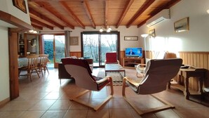 A spacious living room with wooden beams, a television, and a dining area with chairs and a table. - Cottage in Lachapelle-Auzac with Pool (LACHAPELLE AUZAC)