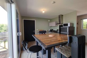A modern kitchen with a wooden table, bar stools, and a microwave. - Home with Mezzanine, Souillac (SOUILLAC)