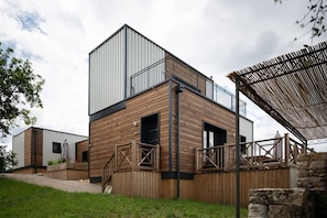 A modern building with a wooden facade, a balcony, and a covered outdoor area. - Home with Mezzanine, Souillac (SOUILLAC)