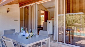Uma área de jantar com uma mesa posta para quatro pessoas, geladeira e vista para uma piscina.