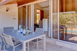 Zona pranzo con tavolo apparecchiato per quattro, frigorifero e vista su una piscina.
