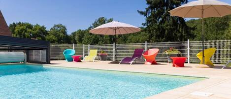 Una piscina con sillones de playa y sombrillas coloridas.