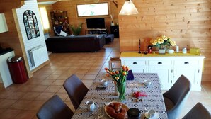 A cozy room with a dining table set for two, a sofa, and a television in the background. - Home with Enclosed Garden near Sarlat (PECHS DE L'ESPERANCE)