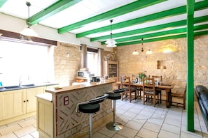 Eine Küche mit einer Steinwand, Holzschränken, einer Bar und einem Esstisch mit Stühlen.