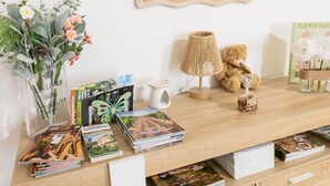 A wooden table with magazines, a vase of flowers, a lamp, a teddy bear, and a framed mirror. - Apartment in Martel City Center (MARTEL)