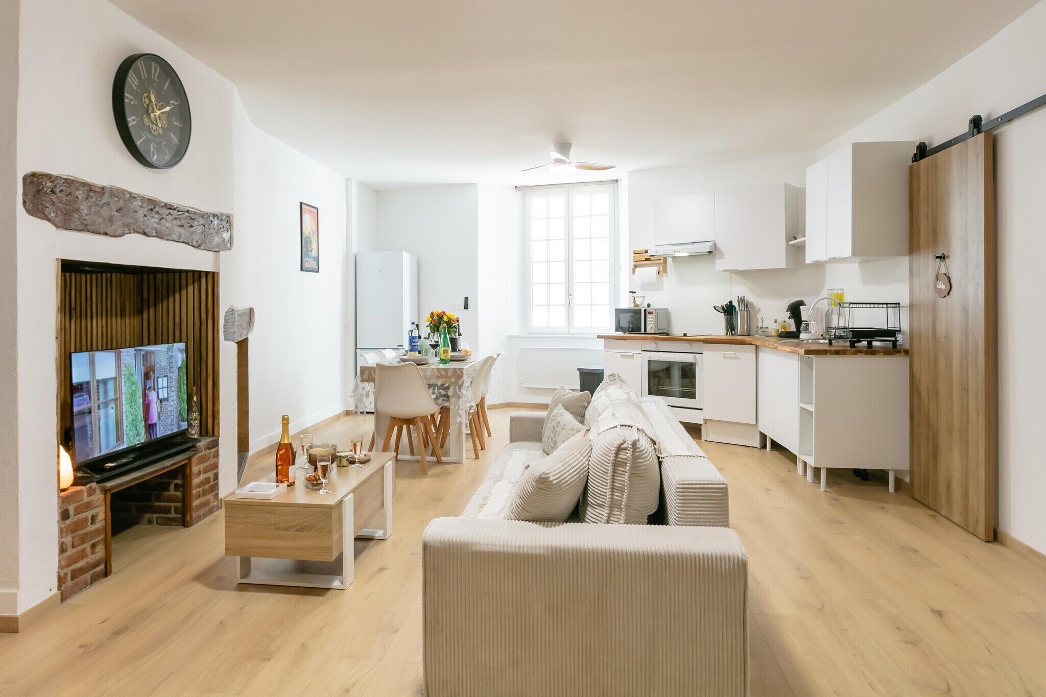 Eine moderne Wohnung mit Wohnzimmer, Essbereich, Küche und einem an einer Ziegelwand befestigten Fernseher.