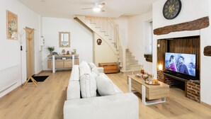 A living room with a sofa, TV, wooden staircase, and a fireplace. - Apartment in Martel City Center (MARTEL)