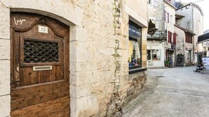 A narrow street with a wooden door marked '13' and a stone building with a balcony. - Apartment in Martel City Center (MARTEL)