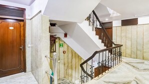 Un hall d’hôtel avec un escalier en marbre, une porte en bois et une plaque portant le numéro « 2 ».