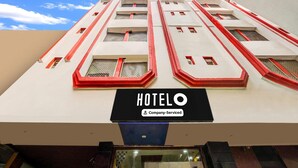 Un hôtel reconnaissable à son grand panneau « HOTELO », à ses nombreuses fenêtres rehaussées de touches de rouge et à son indication « Service d’entreprise ».