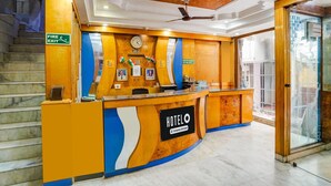 Un comptoir d’accueil d’hôtel avec une horloge, un panneau indiquant la sortie de secours et un ventilateur de plafond.