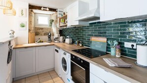 A compact kitchen with a washing machine, a coffee maker, and a toaster. - Bastide Village Retreat in Montfaucon (MONTFAUCON)