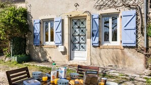 A breakfast table set outside a building with blue shutters, a door, and a window. - Bastide Village Retreat in Montfaucon (MONTFAUCON)