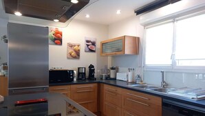 A modern kitchen with a built-in stove, a dishwasher, and a large window. - Charming 4-Bedroom House in the Heart of the Lot (LACHAPELLE AUZAC)