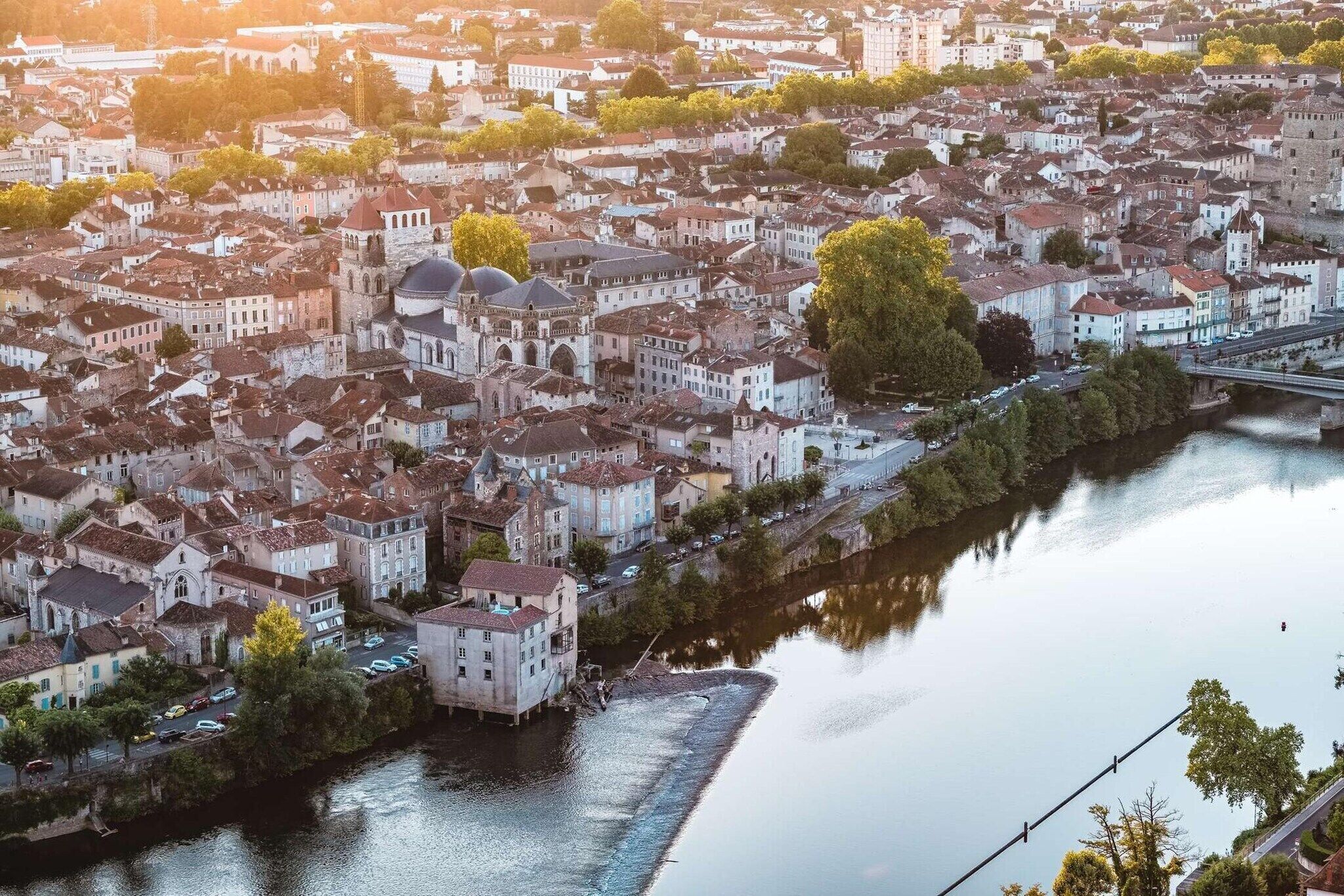 An aerial view of a historic city with a river, buildings, and a bridge.