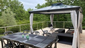 A covered outdoor patio with a table and chairs, a seating area, and a pergola structure. - Charming 4-Bedroom House in the Heart of the Lot (LACHAPELLE AUZAC)