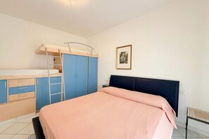 Een slaapkamer met een bed, een kledingkast, een bureau en een ladder.