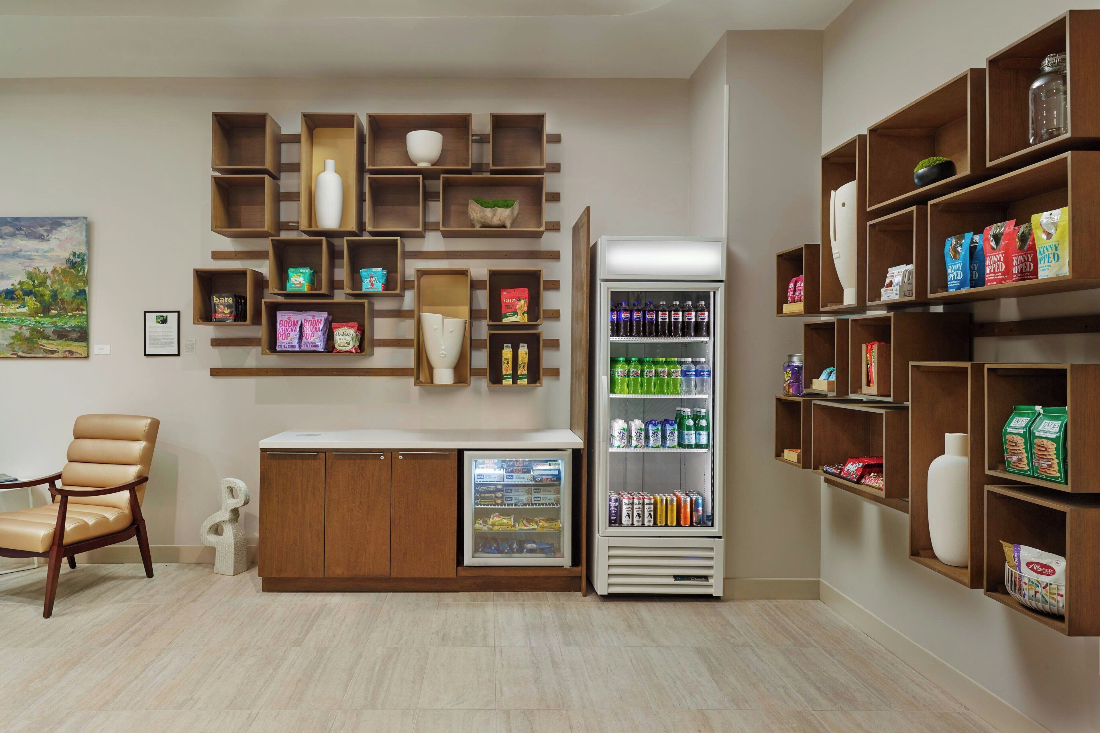 Una habitación con zona de estar, refrigerador y estantes con diversos objetos.